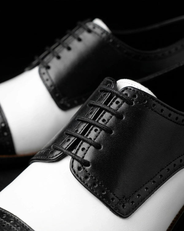 Bold & Brogue Close-up of black and white two-tone brogue shoes showing leather laces and perforated detailing