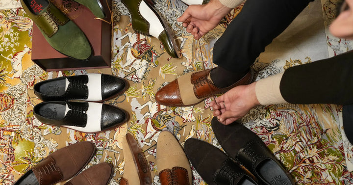Cueřo founder refining a handcrafted cognac leather dress shoe among a curated collection of men’s luxury footwear
