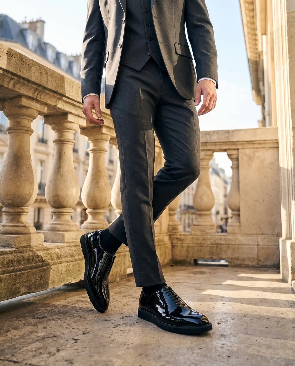 Man in a tailored black suit wearing polished black leather formal shoes.