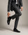 Person wearing a gray suit and Regal black shoes on a plain background