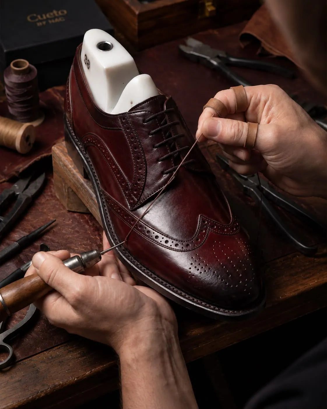 Artisan silk-stitching a leather brogue shoe upper at nine stitches per inch with blind seams concealed within